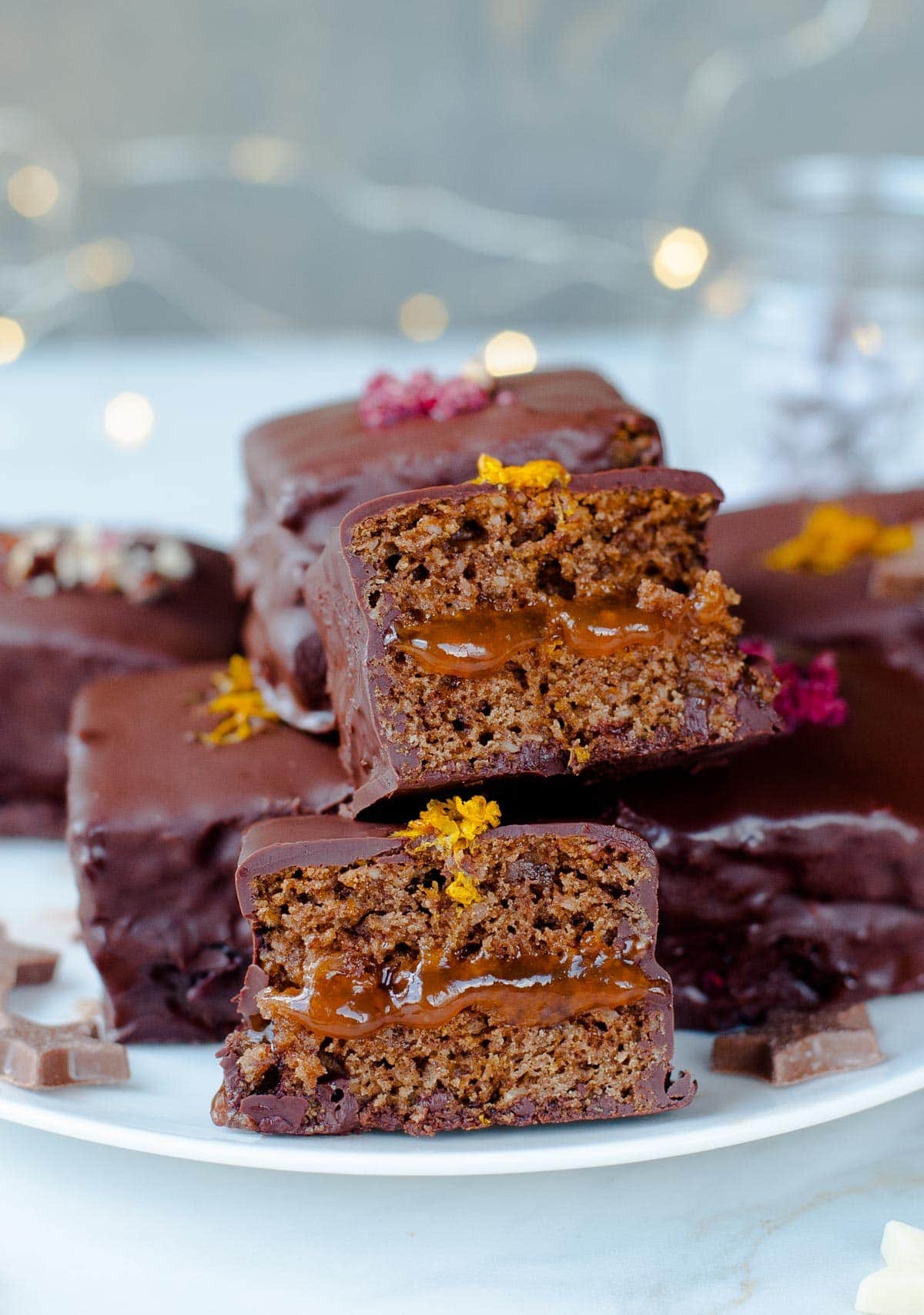 Lebkuchen cookie squares filled with plum jam and coated in chocolate on a plate.