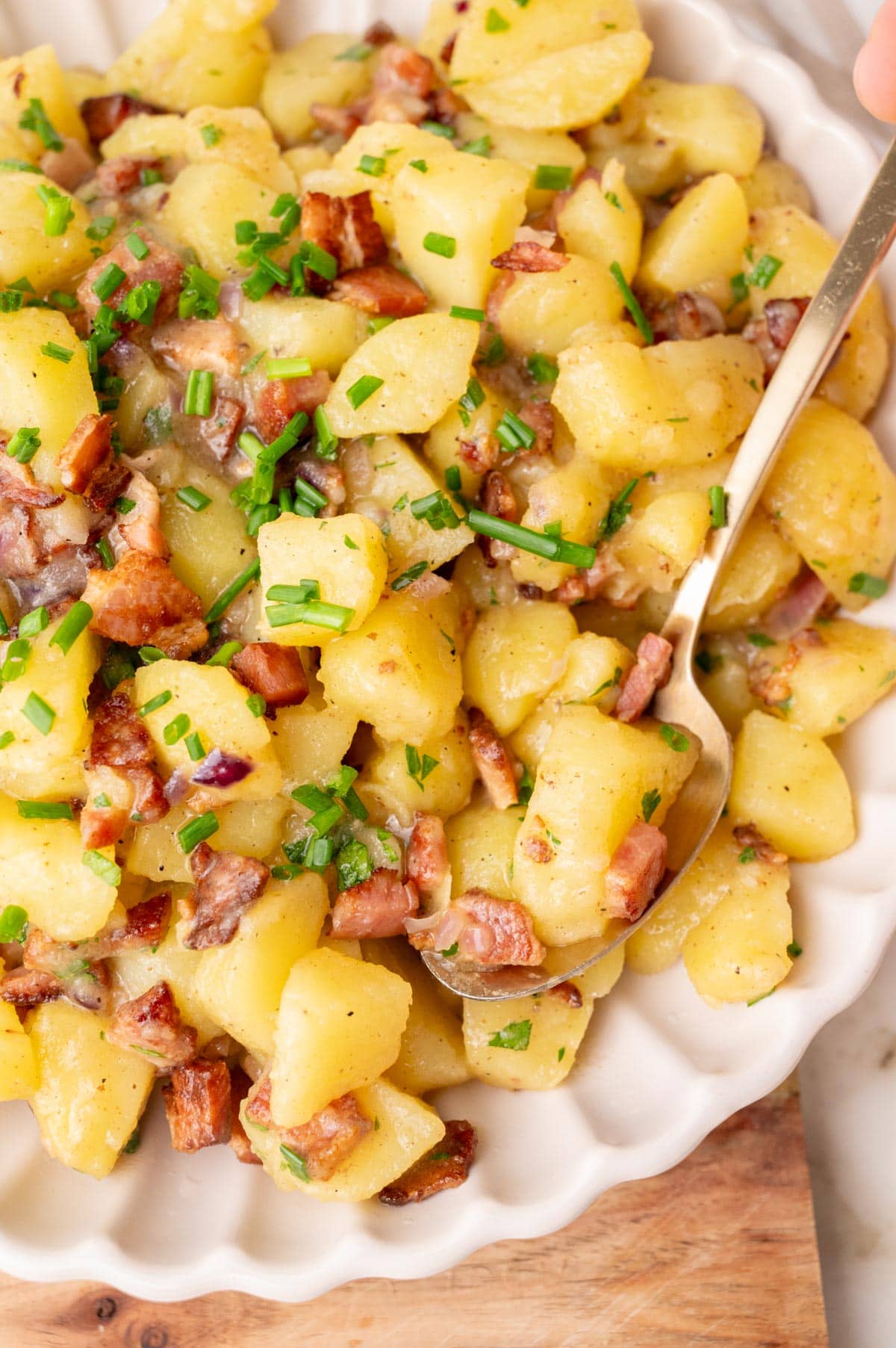 A close-up photo of German potato salad in a beige bowl.